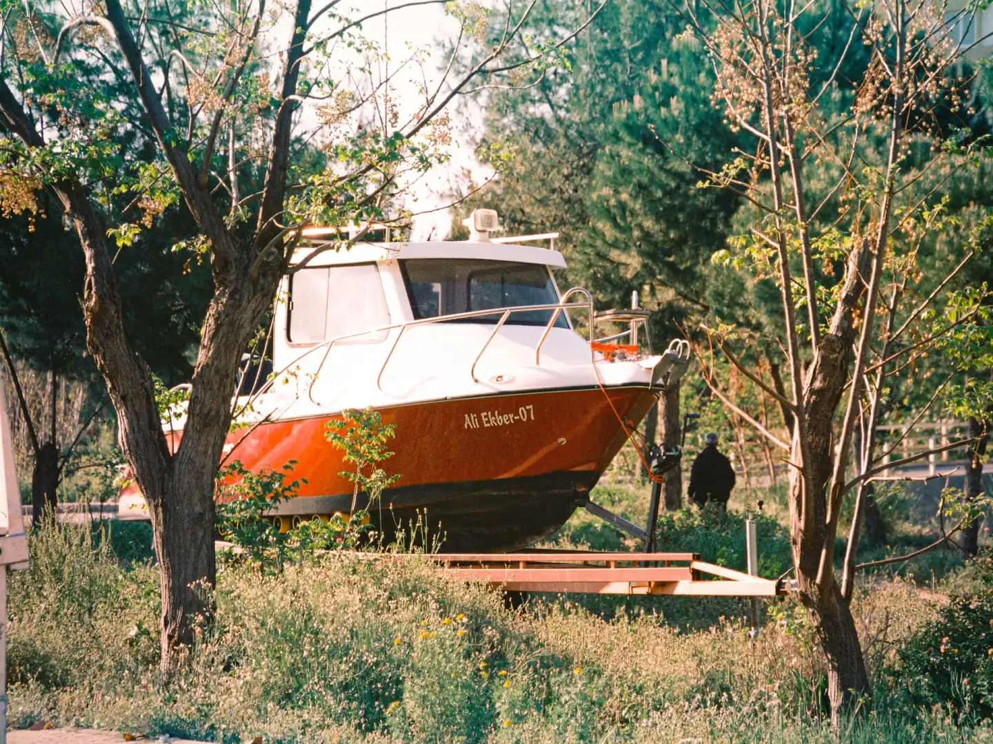 A boat sitting on its trailer on a grass field