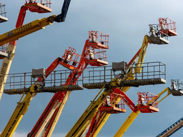 Boom lifts raised against a clear blue sky
