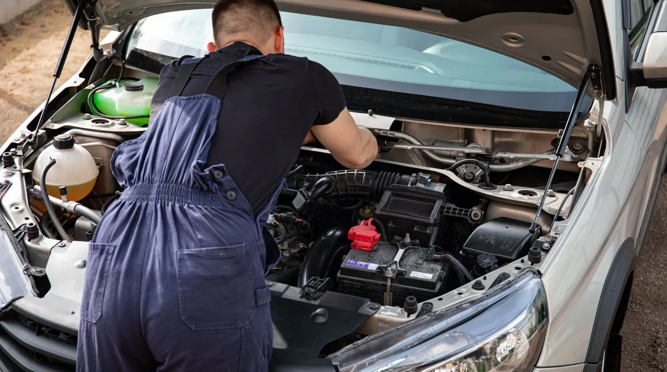 Close view of a mechanic repairing a car engine outdoors