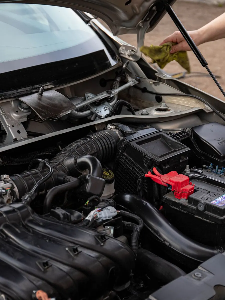 A mechanic inspecting an engine bay and battery