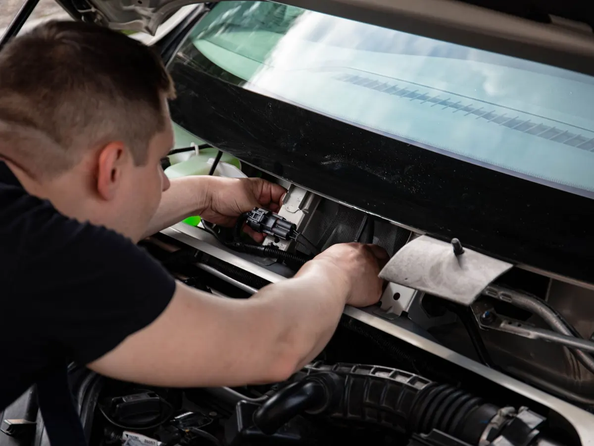 A mechanic working under the hood of a car