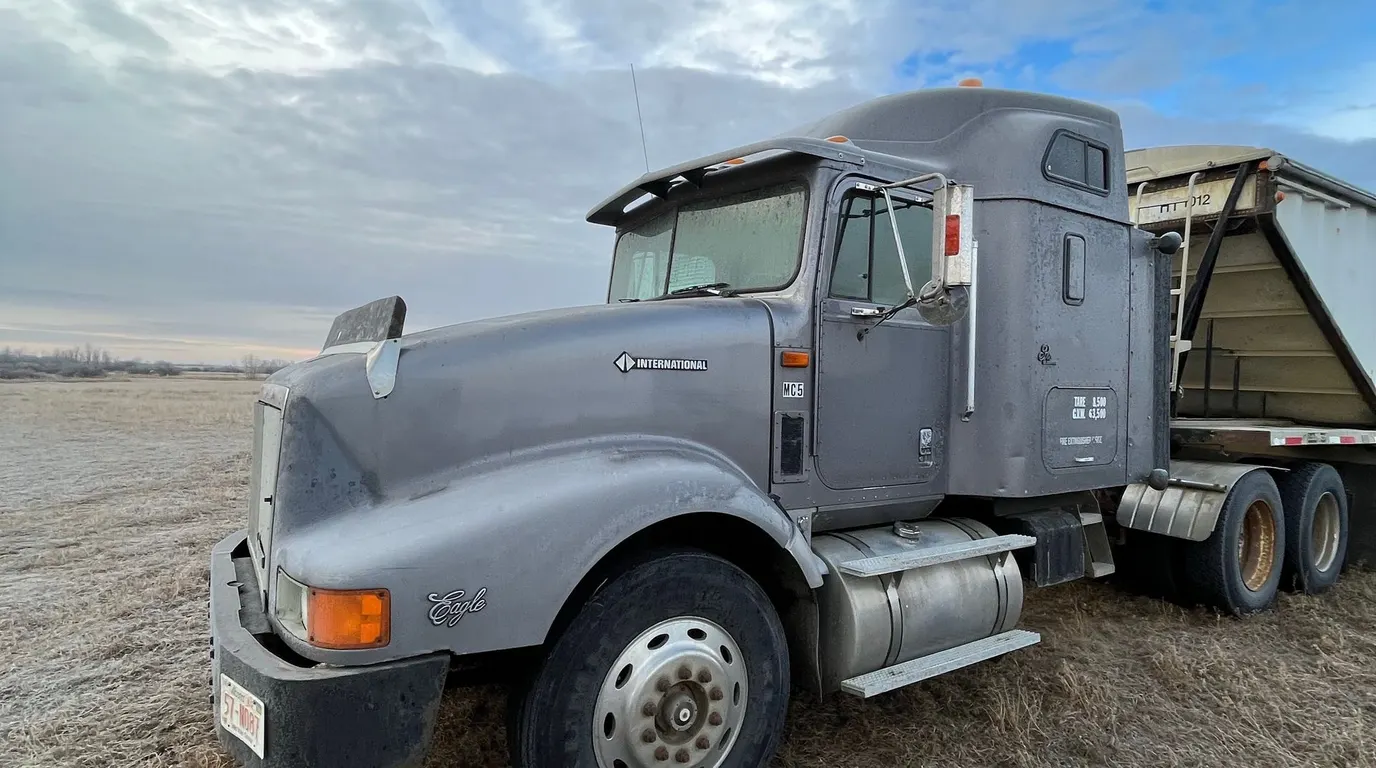 A semi truck stopped on dry ground under a blue sky