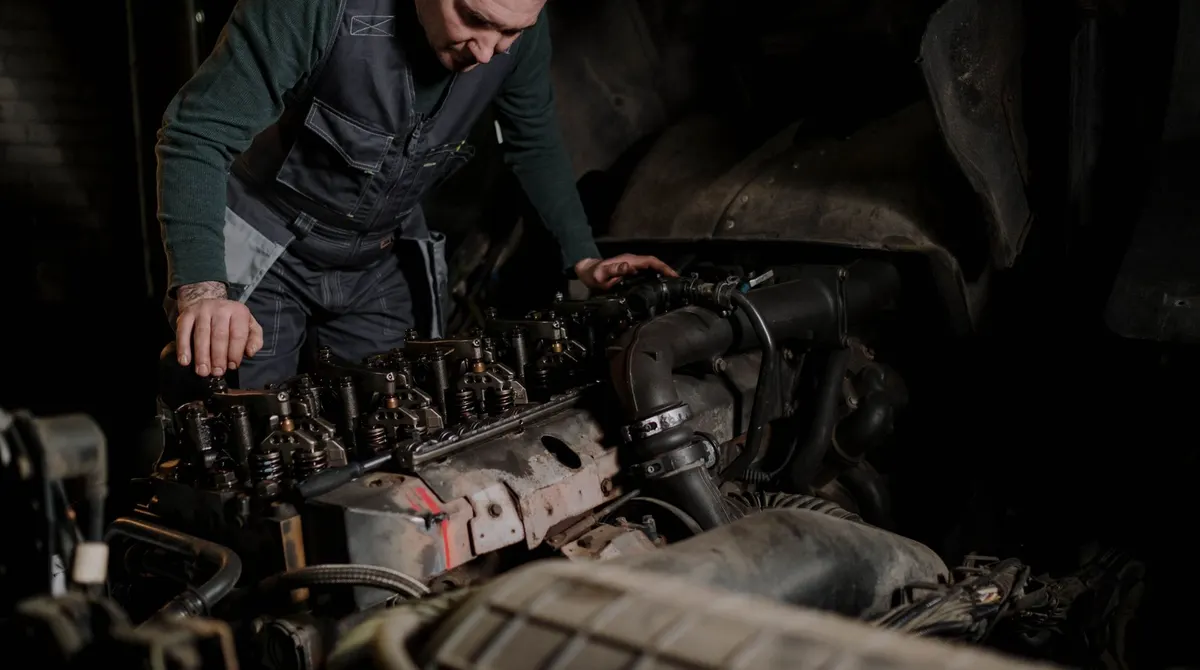 A mechanic working on a truck engine inside a workshop